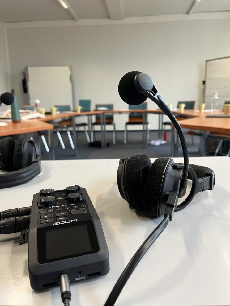 Ein Recorder und ein Podcast Headset auf einem Tisch in einem Seminarraum
